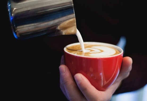 Cappuccino with latte art, poured into a red cup