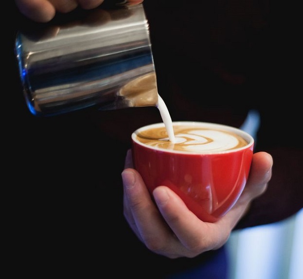 Cappuccino cu latte art, turnat într-o ceașcă roșie