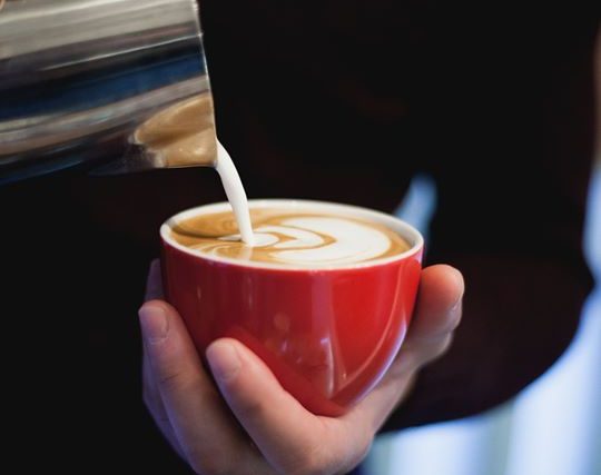 Flat white with latte art, poured into a red cup
