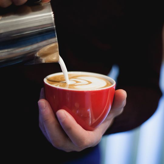 Flat white cu latte art, turnat într-o ceașcă roșie