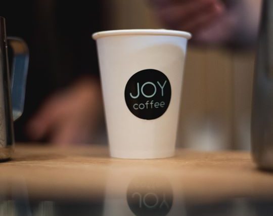 A JOY coffee cup held in hand