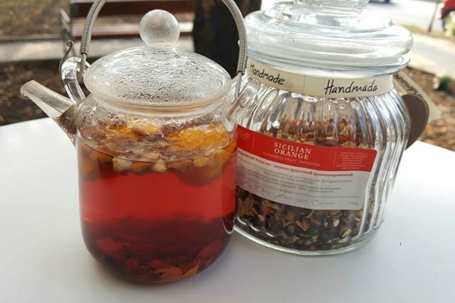 Fruit tea in a glass teapot, next to the jar of loose infusion