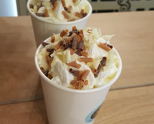 Hot chocolate with whipped cream and chocolate curls, in a takeaway cup