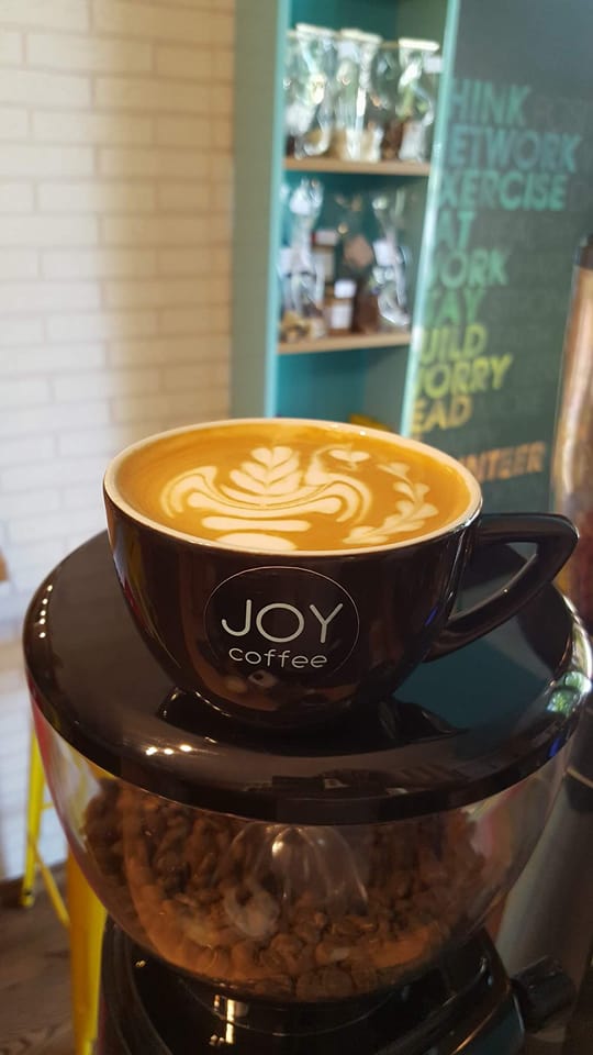 Caffe latte cu latte art, în ceașcă JOY coffee, pe râșniță